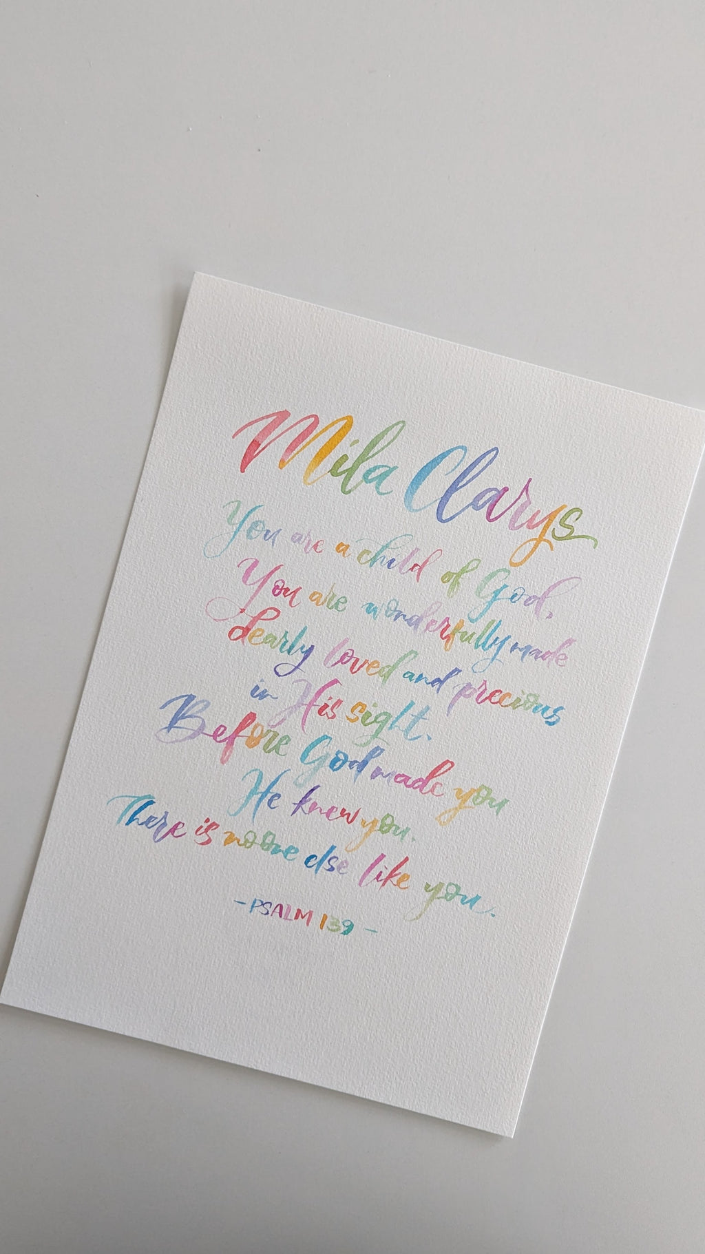A white rectangular art print featuring colorful hand-lettered text on a light gray background. The text includes the name 'Mila' in rainbow script and a Bible verse from Psalm 142.