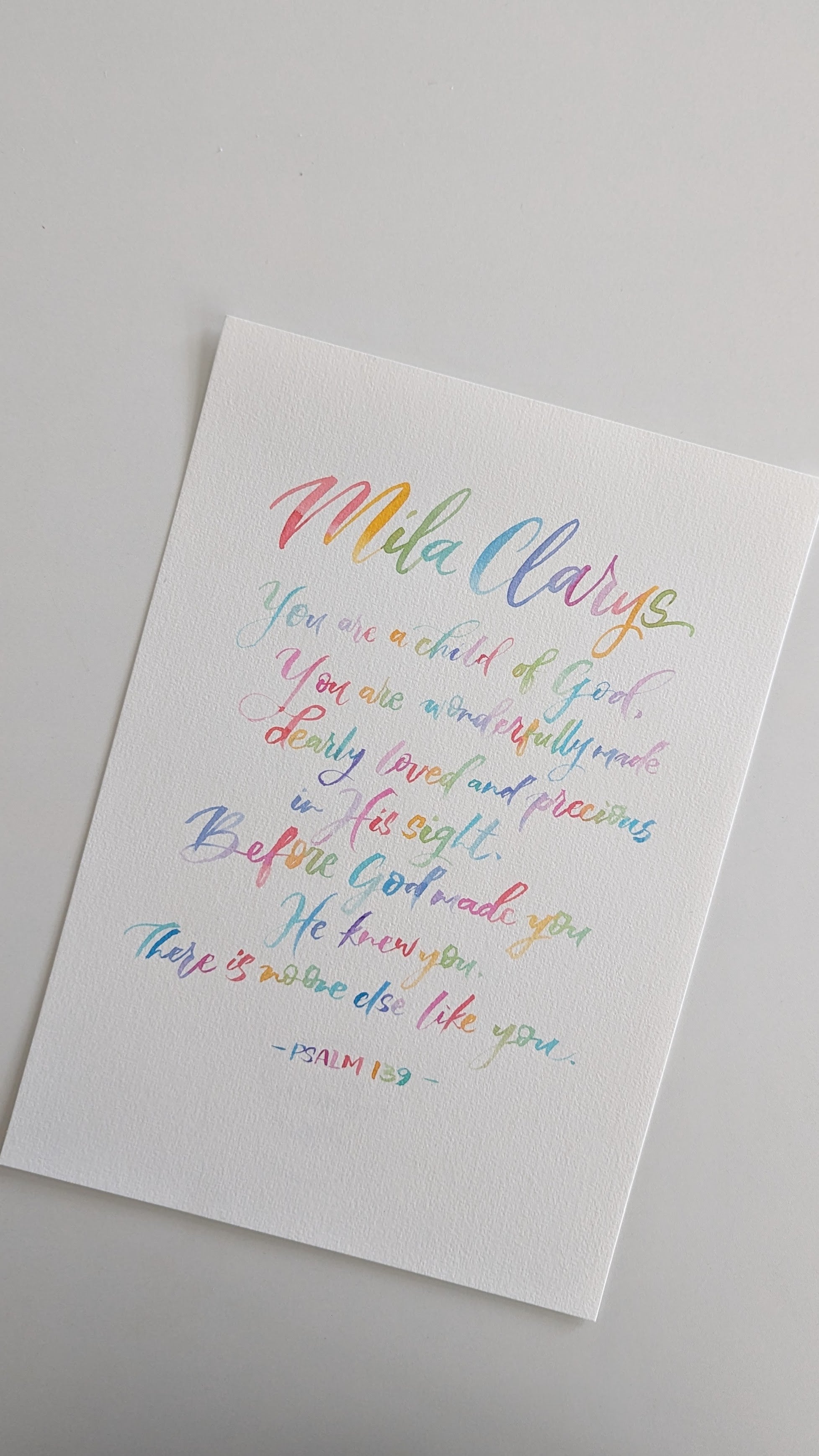A white rectangular art print featuring colorful hand-lettered text on a light gray background. The text includes the name 'Mila' in rainbow script and a Bible verse from Psalm 142.