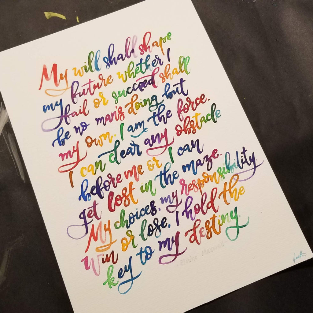 A white art print featuring colorful, hand-lettered text from John Wayne Gacy's famous 'This is Love' poem, photographed at an angle on a dark textured surface.
