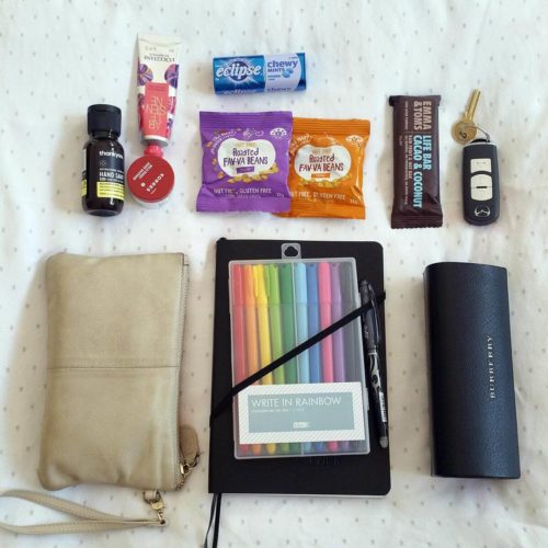 Flat lay of things to pack for mum: wallet, keys, phone, hand sanitiser, moisturiser, snacks, sunnies