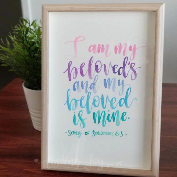 Original, hand-painted brush-lettered artwork of quote "I am my beloved's and my beloved is mine" - Song of Solomon 6:3 written in different types of pink, purple, blue and turquoise watercolour paint on A4 300GSM card.