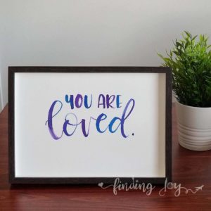 Original, hand-painted brush-lettered artwork of the words “You are loved”.