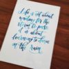 Original, hand-painted brush-lettered artwork of the quote "Life is not about waiting for the storm to pass, it is about learning to dance in the rain" written in different types of blue watercolour on A4 300GSM card. © Joy Adan 2018