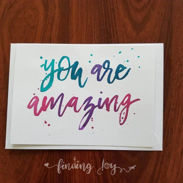 Greeting card with "you are amazing" hand-lettered in turquoise, teal, purple and magenta Ecoline ink.