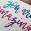 Greeting card with "you are amazing" hand-lettered in turquoise, teal, purple and magenta Ecoline ink.