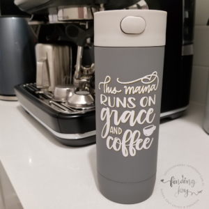 Grey insulated travel bottle with “This mama runs on grace and coffee” hand-lettered on white vinyl