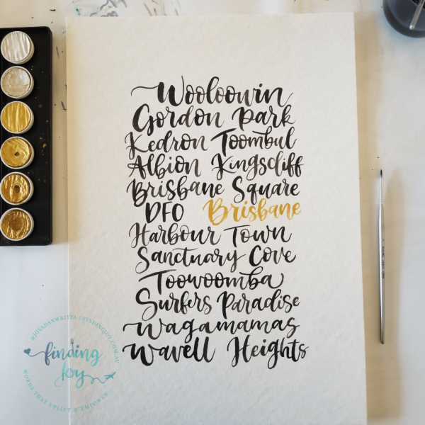 Paper Anniversary Gift - A3 watercolour sheet with cities and suburbs hand-lettered in black and gold ink. Painting with suburbs hand-painted in black and gold ink. Words include Brisbane, Harbour Town and Sanctuary Cove.